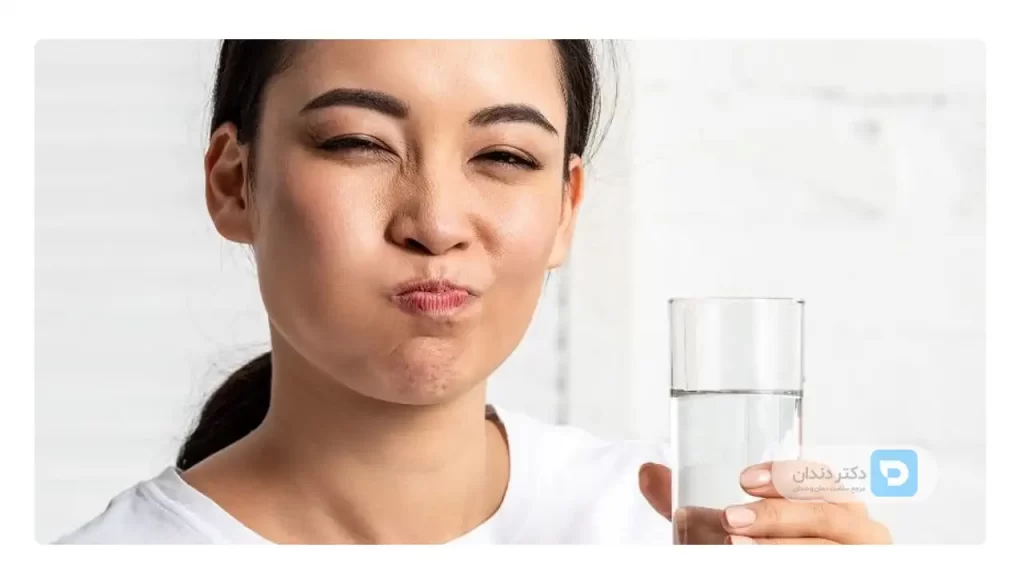 خانمی که در حال غرغره کردن آب در دهان برای کاهش علائم سنگ لوزه است