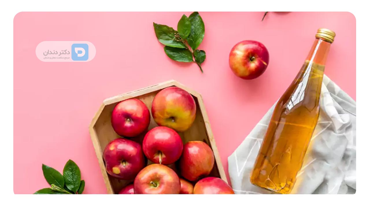 عکس سرکه سیب و چند عدد سیب سرخ روی یک میز
